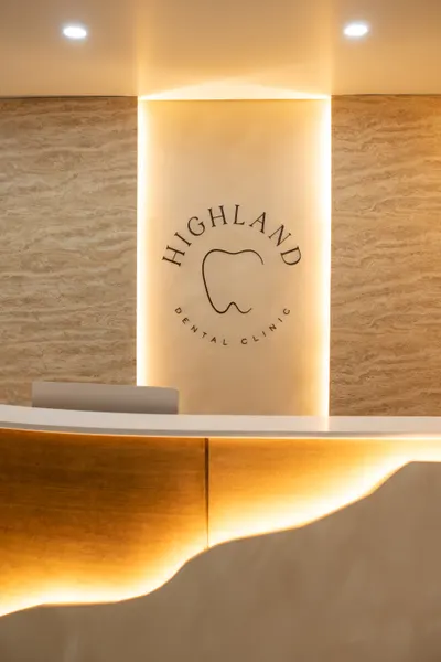 The Allure Dental reception alcove with a backlit travertine niche and sculpted wood front desk