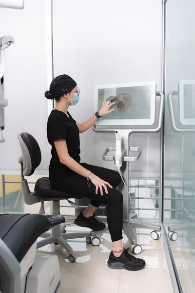 Dental team member reviewing a tooth diagram on a treatment-planning workstation