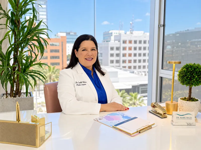 Dr. Isabel Balza at her desk in her Tijuana office, with the city skyline behind her