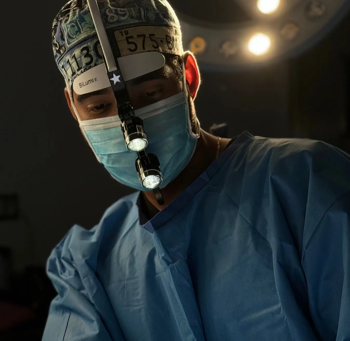 Dr. Luis Monta&ntilde;o in surgical scrubs and loupes during a facial procedure