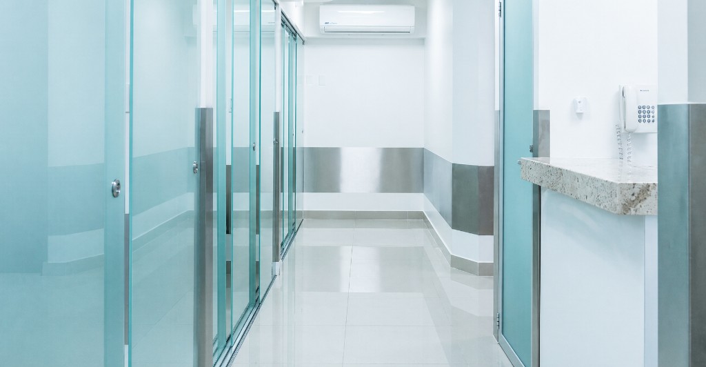 Mint frosted-glass treatment hallway with intercom counter at the Tijuana clinic