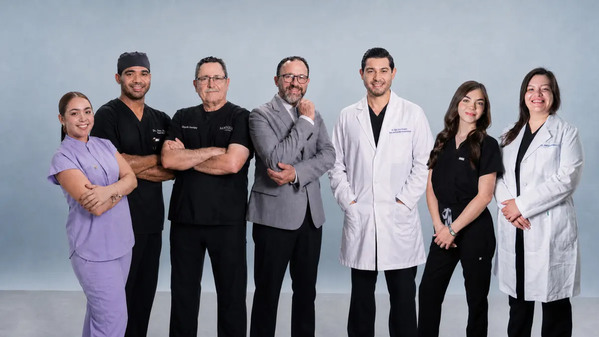 Editorial group portrait of the Allure RT MX surgeons, anesthesia team, dental leads, Lead Patient Coordinator Natalia Gonzalez, and Dra. Marla Rodriguez on a soft blue studio backdrop