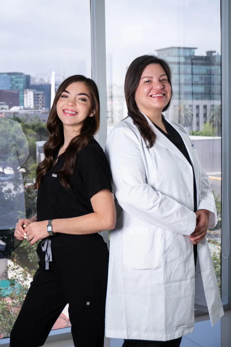 Allure RT MX leads Dra. Marla Rodriguez and Natalia Gonzalez standing back-to-back at the Tijuana clinic, with the city skyline visible through the window behind them.