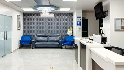 Waiting lounge at Hospital Bellas Artes with blue armchairs and a television