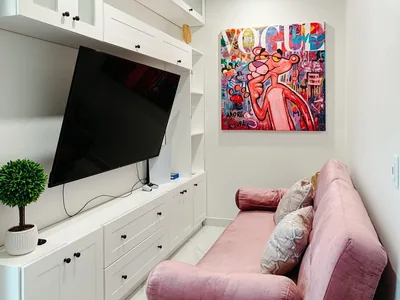 Lounge area of a private suite at Hospital Bellas Artes with pink sofa, television, and colorful art