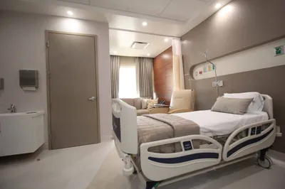 Private patient suite at Hospital SIMNSA with an adjustable bed, sofa seating, and warm lighting