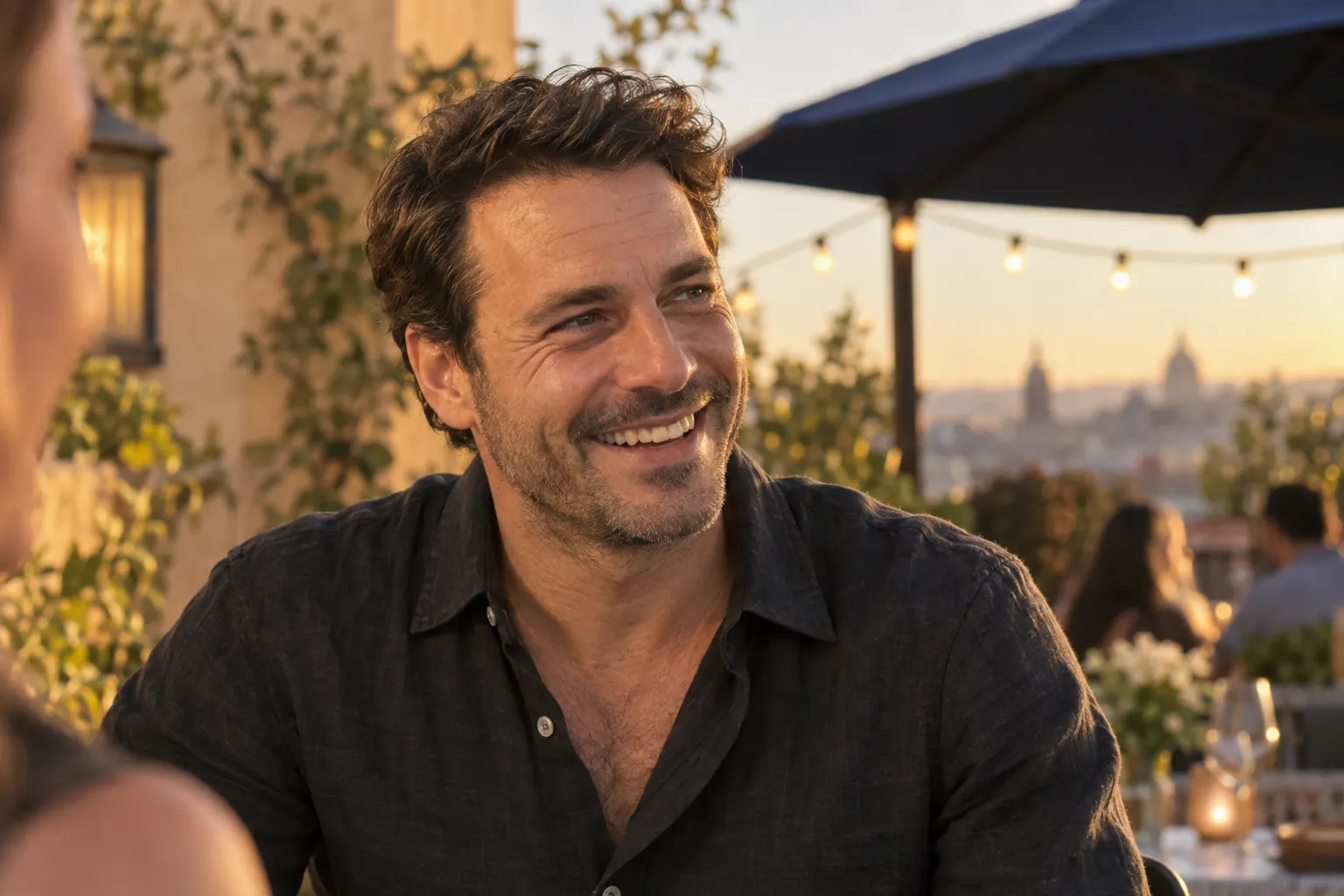 Man in his forties laughing on a golden-hour terrace with a full, natural head of hair after an FUE transplant