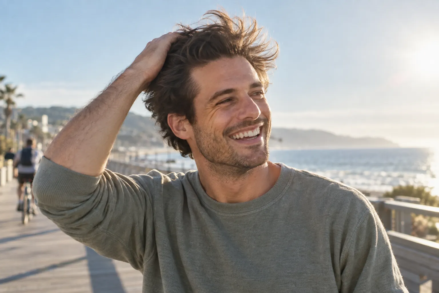 Young man on a breezy coastal boardwalk pushing back thick healthy hair after PRP hair restoration